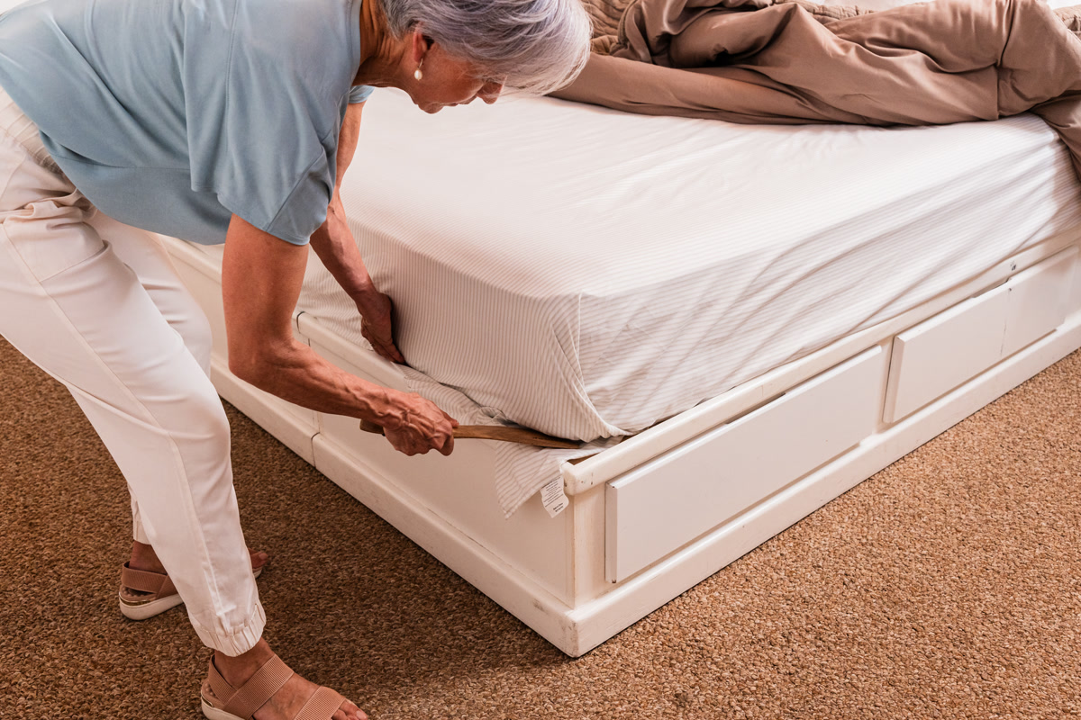 A woman tucking a fitted sheet corner with the tucker